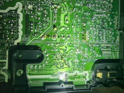 Zbliżenie na zieloną płytkę drukowaną z różnymi elementami elektronicznymi.