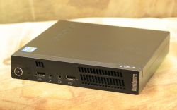 Mały komputer Lenovo ThinkCentre M72e na beżowym tle.