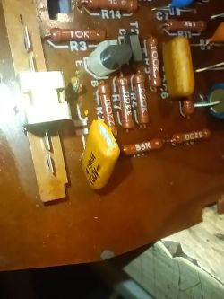 Zbliżenie płytki PCB z rezystorami, kondensatorem żółtym i trymrem obok złącza
