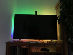TV screen on wooden cabinet with RGB backlight and visible cables