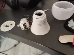 Disassembled LED light bulb parts on a black table.