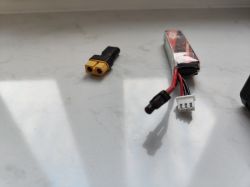Bateria do drona FPV z dwoma rodzajami złączy na białym tle.