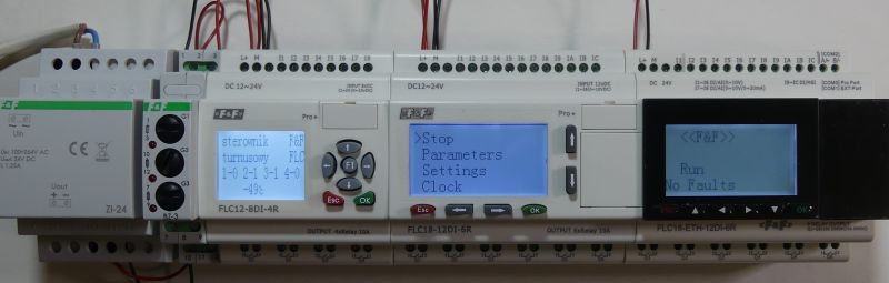 Sterowniki programowalne PLC z wyświetlaczami LCD zamontowane na szynie DIN.