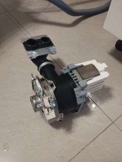 Pompa zmywarki z widoczną elektryczną częścią, leżąca na podłodze.