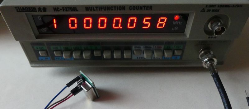 Multifunkcyjny miernik częstotliwości z wyświetlaczem LED pokazującym 10 000 058 Hz oraz podłączony generator TCXO.