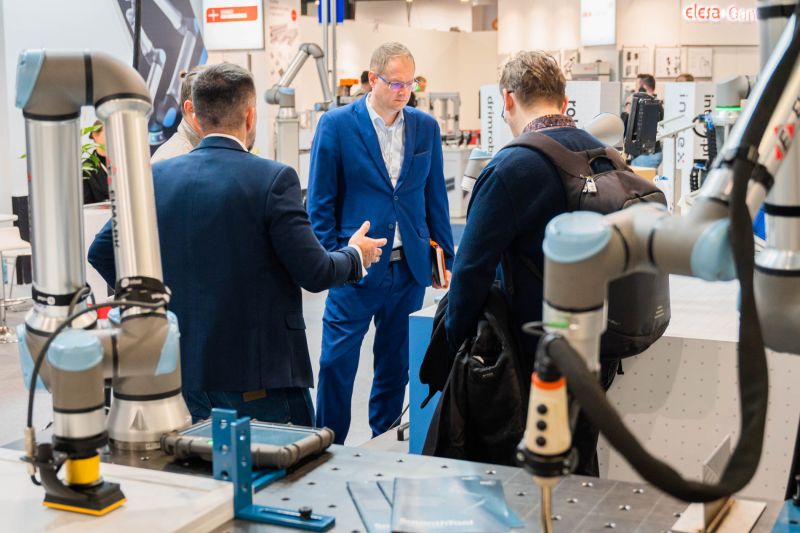 Group of men talking at a booth with industrial robots at a tech trade fair