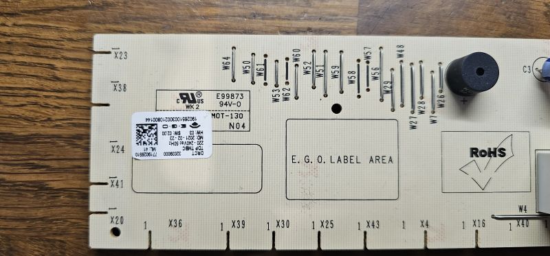 Płytka PCB z oznaczeniami technicznymi, naklejkami i elementami elektronicznymi