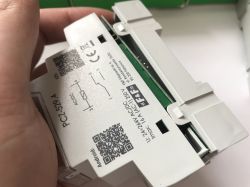 Ręka trzymająca moduł elektryczny z nadrukiem PC1-529.A i kodami QR.