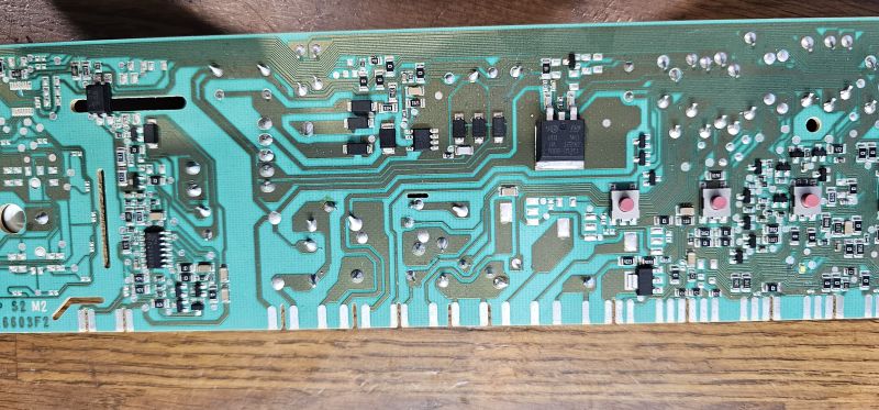 Zbliżenie na zieloną płytkę PCB z licznymi ścieżkami, lutami i podzespołami elektronicznymi.
