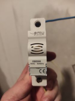 Osoba trzymająca w dłoni urządzenie z oznaczeniem OBE008 i logotypem OMU System.