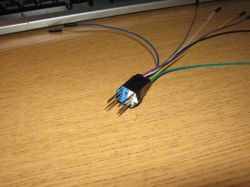 Wtyczka USB z ośmioma metalowymi szpilkami i kilkoma kolorowymi przewodami na biurku.
