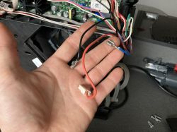 Dłoń trzymająca trzy przewody od płytki drukowanej w urządzeniu elektronicznym.