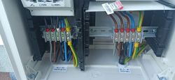 Widok wnętrza rozdzielnicy elektrycznej z kolorowymi przewodami i terminalami.