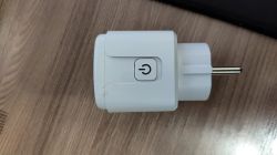 White plug with a power button lying on a wooden floor