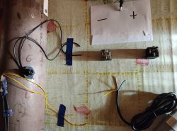 Przewody czarne i żółte przymocowane do rury, elementy elektroniczne na stole