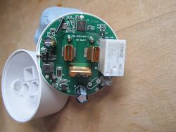 Inside view of a smart plug with exposed PCB Close-up of an opened smart plug showing a green PCB and electronic components.