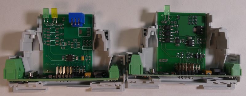 Dwa otwarte moduły elektroniczne na szynie DIN z widocznymi płytkami drukowanymi i złączami.