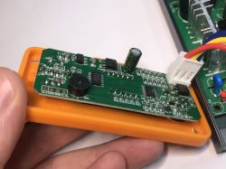 Zbliżenie na płytkę elektroniki w plastikowej obudowie lutownicy, widoczne elementy SMT i przewody zasilające.