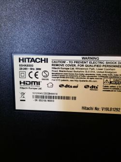 Back label of a Hitachi 65HK6500 TV showing power ratings, warnings, and compliance logos