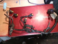 Wiązka kabli samochodowych na czerwonym laptopie z widocznymi złączami.