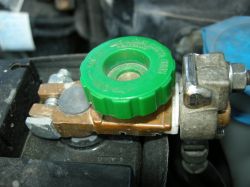 Wyłącznik akumulatora zamontowany na klemie z zielonym pokrętłem.