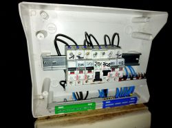 Skrzynka elektryczna z widocznymi bezpiecznikami i przewodami.
