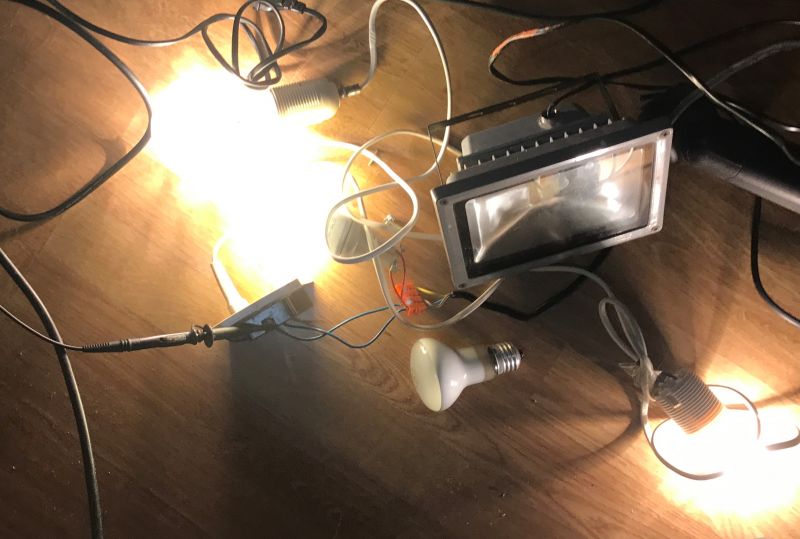 Lampy żarowe i LED oraz przewody elektryczne rozłożone na podłodze.