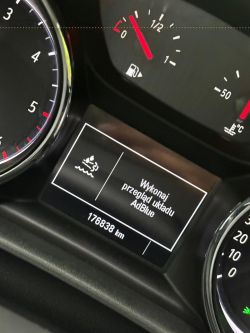 Wyświetlacz komputera pokładowego samochodu pokazujący komunikat Wykonaj przegląd układu AdBlue.
