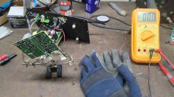 Multimetr cyfrowy i układ elektroniczny na stole warsztatowym.
