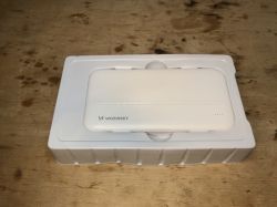 Biały powerbank Wozinsky WPBWE1 w plastikowym opakowaniu na drewnianym tle.