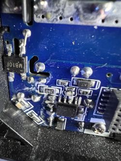 Close-up of the internal side of a blue printed circuit board with various electronic components.