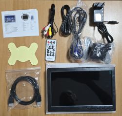 Portable monitor kit: screen, remote, power adapter, and HDMI, VGA, and AV cables on a wooden surface