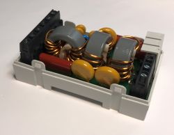 Electronic EMC filter with coils and capacitors in a DIN rail enclosure.