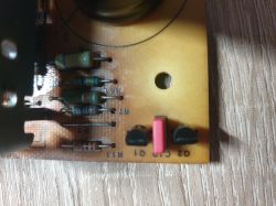 Zbliżenie na płytkę PCB z elementami elektronicznymi, w tym rezystorami i przyciskami.