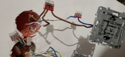 Zbliżenie na instalację elektryczną z widocznymi kablami i złączkami w puszkach.