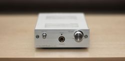 Silver headphone amplifier on a wooden surface.
