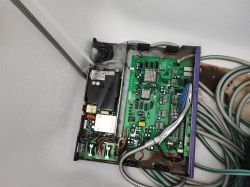 Otwarta obudowa starego switcha sieciowego myta wodą prysznicową w wannie, widoczne płytki PCB i okablowanie.