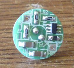 Okrągła płytka PCB z układem MCP1624 i elementami SMD na drewnianym tle