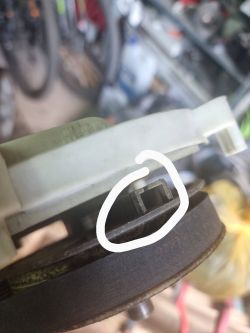 Zbliżenie na mechanizm hamulca tarczowego w kosiarce elektrycznej z zaznaczonym klockiem hamulcowym.