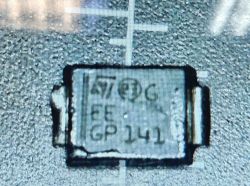Zbliżenie na element SMD ST z nadrukiem „EC” i „GP 141” na płytce PCB