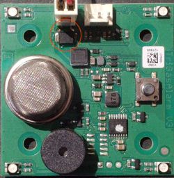 Zbliżenie na małą płytkę elektroniczną z różnymi komponentami, w tym okrągły element i dioda oznaczona jako SMAJ12A DO214AB.