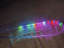 LED strip light illuminating in various colors on a carpeted floor.