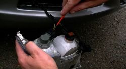 Osoba pracuje nad reflektorem samochodowym trzymanym w dłoniach.