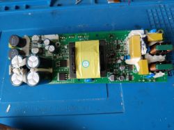 Zasilacz elektroniczny z kondensatorami i cewkami na zielonej płytce PCB.