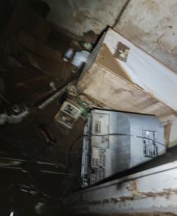 Flooded room with various items covered in mud and sludge.
