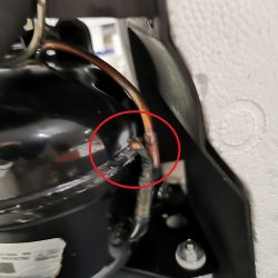 Sprężarka z widocznym śladem wycieku czynnika chłodzącego na spawie.