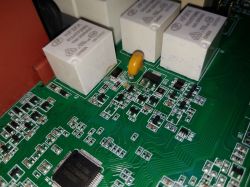 Zbliżenie na płytę elektroniczną z kilkoma przekaźnikami i elementami.