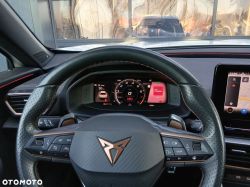 Driver’s view of a steering wheel with Cupra logo, digital instrument cluster, and navigation screen.