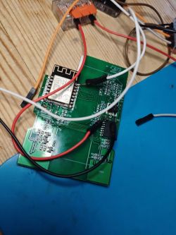 Circuit board with a Wi-Fi module and connected wires on a wooden table.