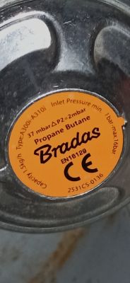 Pomarańczowa etykieta reduktora gazu Bradas z napisem Propane Butane, oznaczeniami technicznymi i certyfikatem CE.
